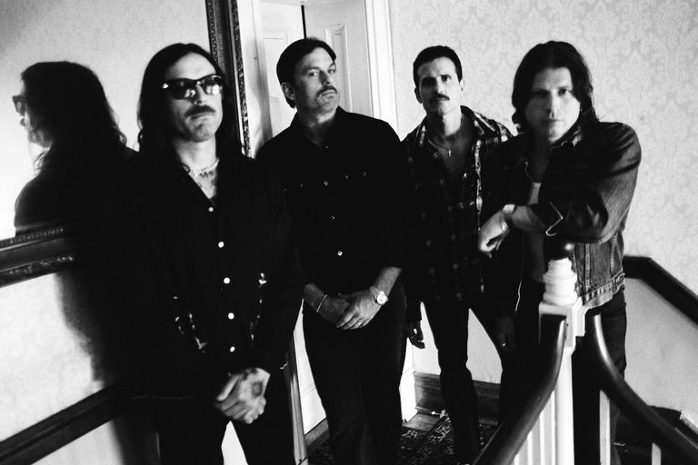 Black and white portrait of American rock band Kings of Leon standing in a hallway.